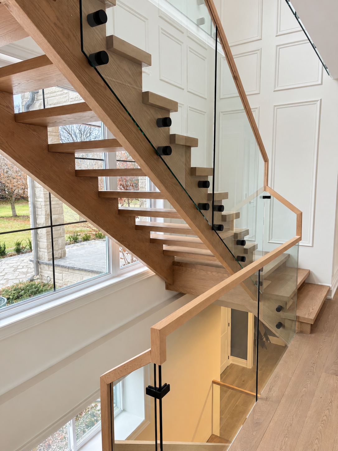 Oak open riser staircase with glass railing and wood handrail